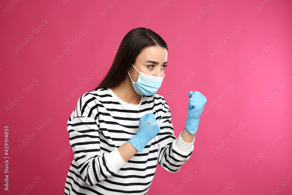 Woman with protective mask and gloves in fighting pose on pink background. Strong immunity concept Woman with protective mask and gloves in fighting pose on pink background. Strong immunity concept
