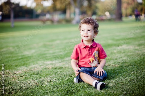 Little Boy Sits on park grass