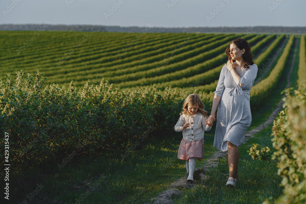 Pregnant mother with her daughter in a field Pregnant mother with her daughter in a field
