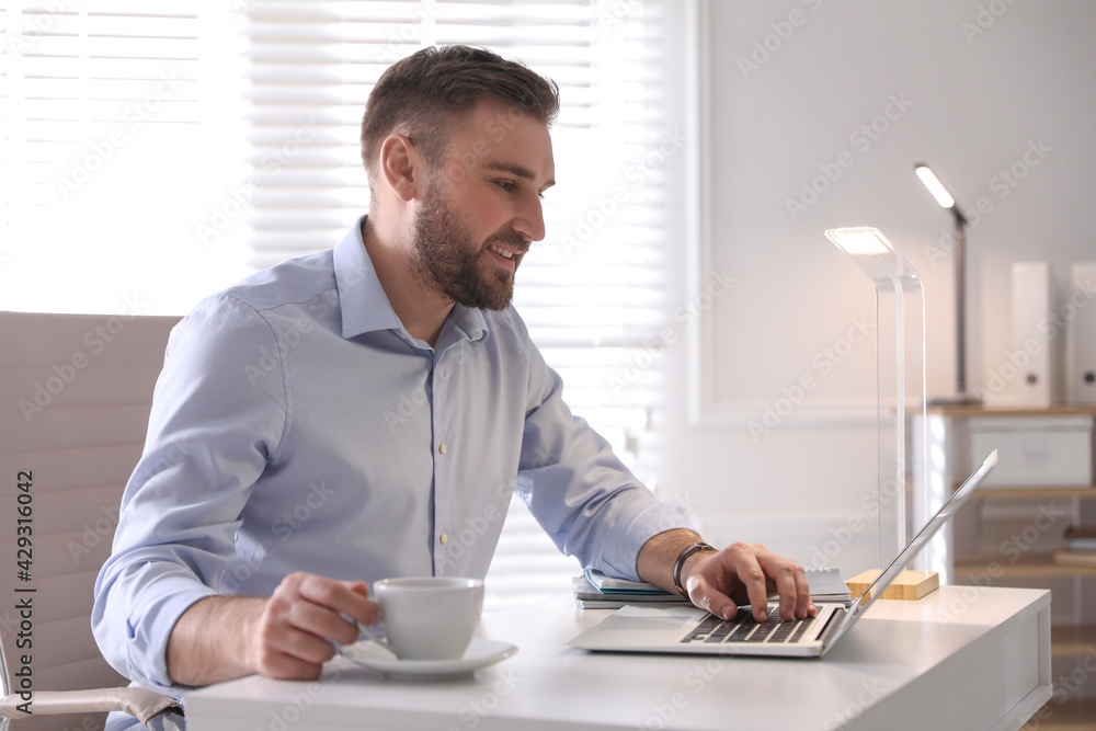 Young man working on laptop at table in office Young man working on laptop at table in office