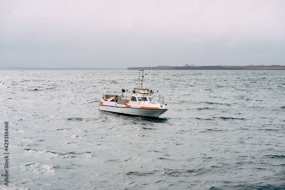 White fishing motor boat sails across the Atlantic Ocean in Iceland. Side view