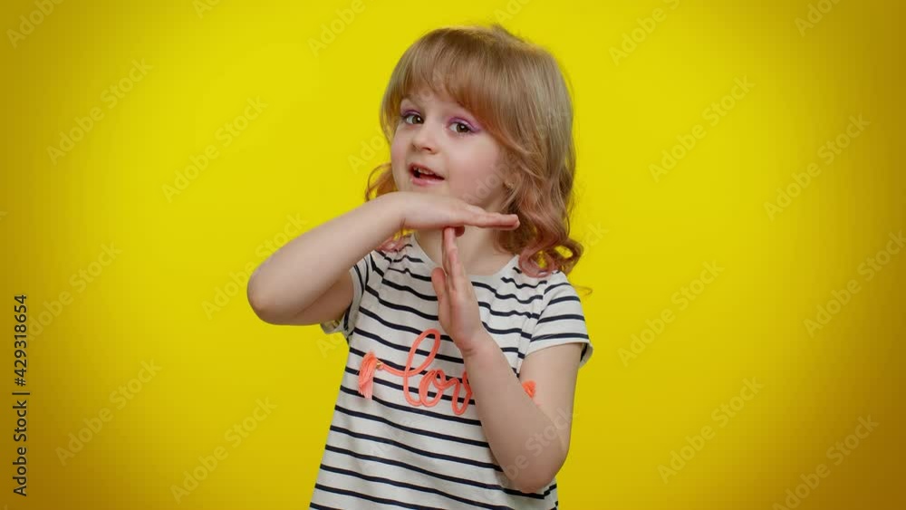 Portrait of serious blonde child girl 5-6 years old in striped t-shirt showing time out gesture, limit or stop sign, no pressure, i need more time on yellow studio wall background. Teen kid children Portrait of serious blonde child girl 5-6 years old in striped t-shirt showing time out gesture, limit or stop sign, no pressure, i need more time on yellow studio wall background. Teen kid children
