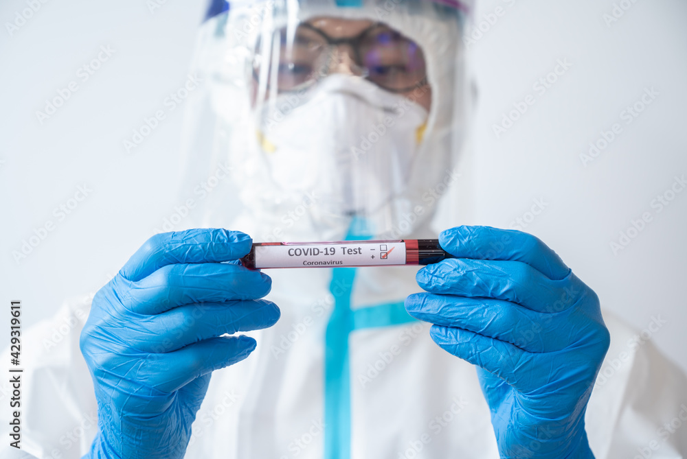 Medical worker in PPE suit holding a sample test tube with blood for 2019-nCoV analyzing. Conceptual of laboratory testing for the respiratory coronavirus disease. Medical worker in PPE suit holding a sample test tube with blood for 2019-nCoV analyzing. Conceptual of laboratory testing for the respiratory coronavirus disease.