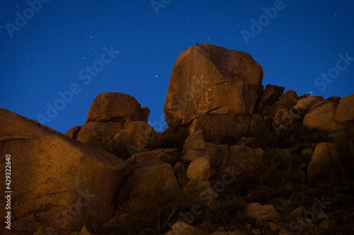 Starry night sky over large rocks on an Arizona desert mountainside