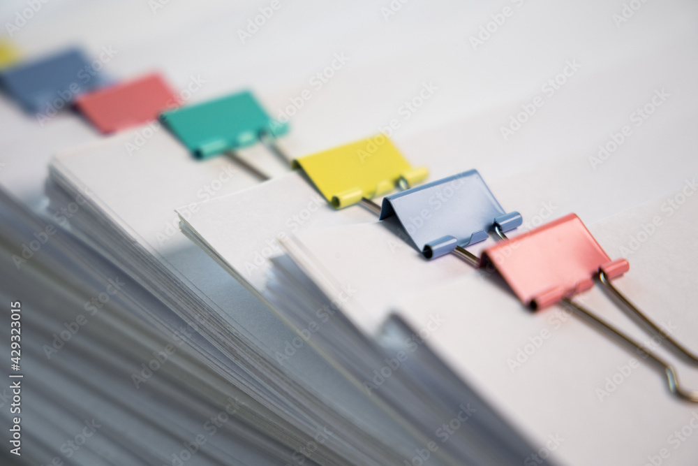 Piles of white papers work large piles of papers stacked together. On the desk in the office with colorful clip. Documents that are not finished in the office. Business concept. Piles of white papers work large piles of papers stacked together. On the desk in the office with colorful clip. Documents that are not finished in the office. Business concept.