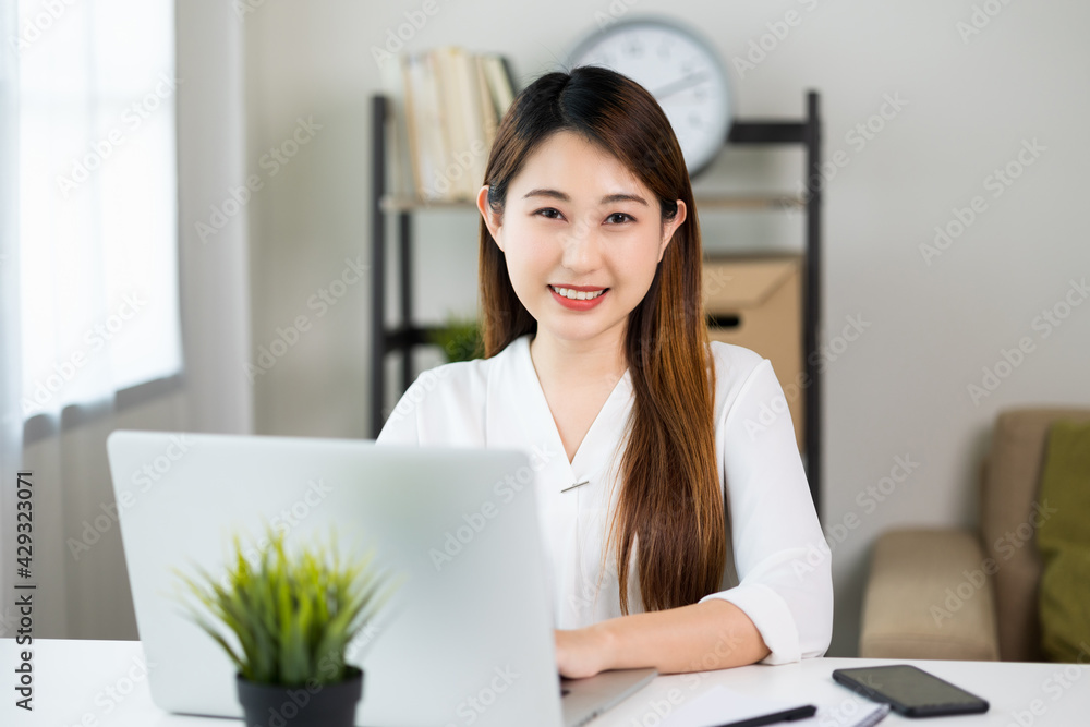 Young asian beautiful business woman working with laptop sitting at home. Smiling charming happy young female doing homework meeting conference with team at home. Young asian beautiful business woman working with laptop sitting at home. Smiling charming happy young female doing homework meeting conference with team at home.