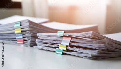 Piles of white papers work large piles of papers stacked together. On the desk in the office with colorful clip. Documents that are not finished in the office. Business concept.