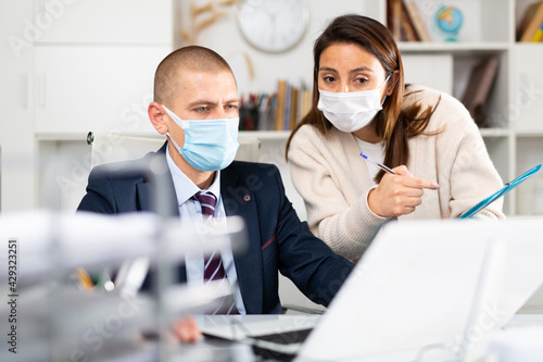 Businessman and businesswoman in protecrive mask working together at office