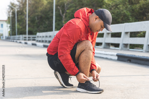 Runners tie their shoelaces prepared to run outdoors. Young asian man wearing sportswear running outdoor.Training athlete work out at outdoor concept.