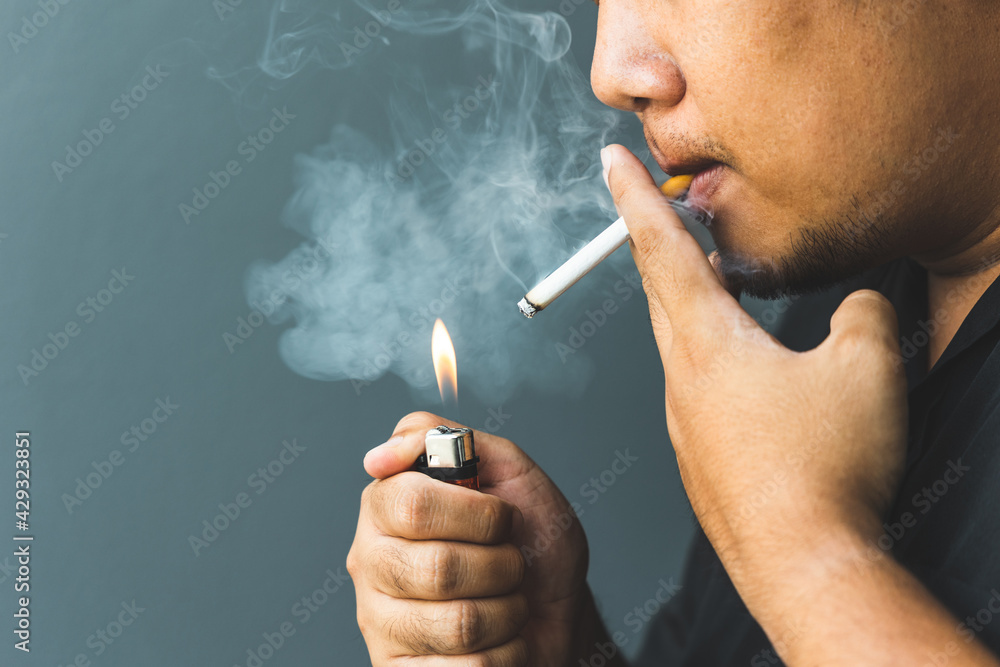 Fototapeta premium A young man with a cigarette He is going to smoke He lit the cigarette lighter with a lighter. world tobacco day.