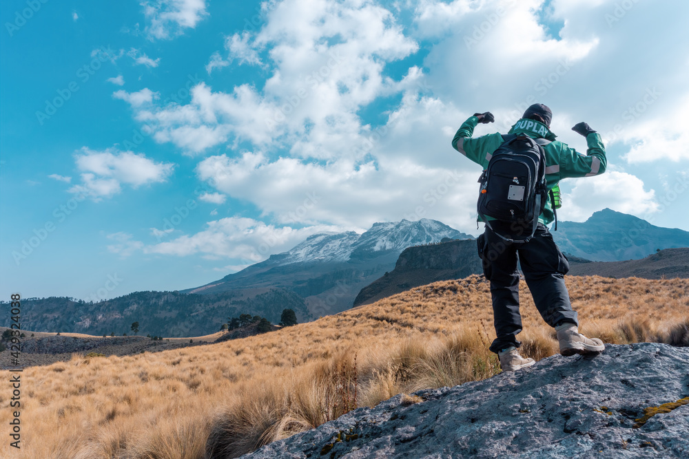 Back view of a tourist showing a winner gesture with the Iztaccihuatl mountain in the background