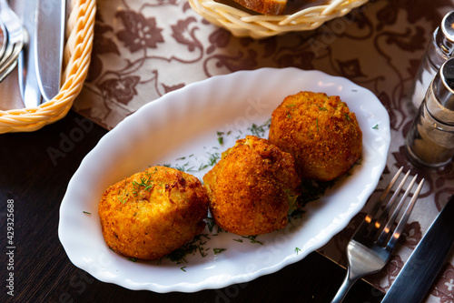 Belarusian cuisine. Appetizing crispy fried potato dumplings with mushrooms (pyzy) served on white plate photo