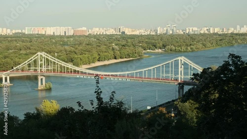 Long elevated view of the people on the Dnipro Pedestrian Bridge on a a warm autumn evening in Kiev photo