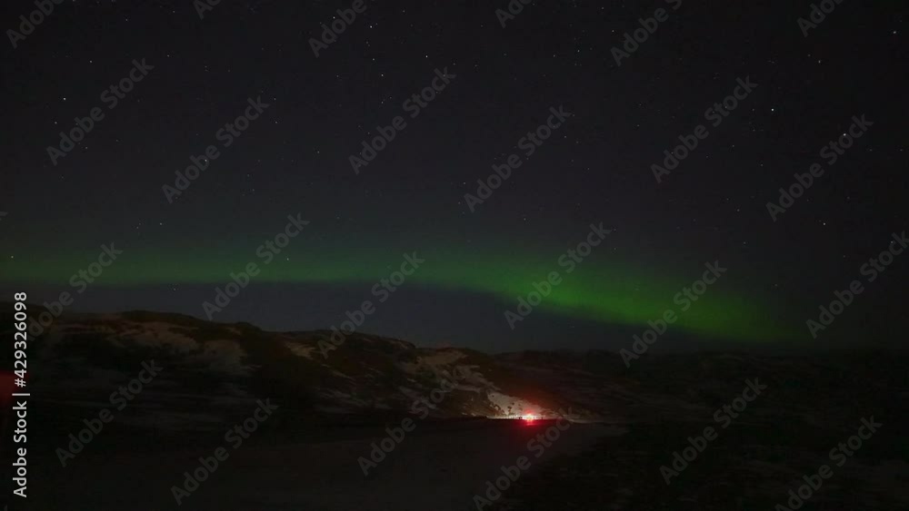Green lighting Aurora Borealis at sky during night and car driving in the valley in Iceland - Wide shot. Visiting spectacular Northern Lights. Green lighting Aurora Borealis at sky during night and car driving in the valley in Iceland - Wide shot. Visiting spectacular Northern Lights.