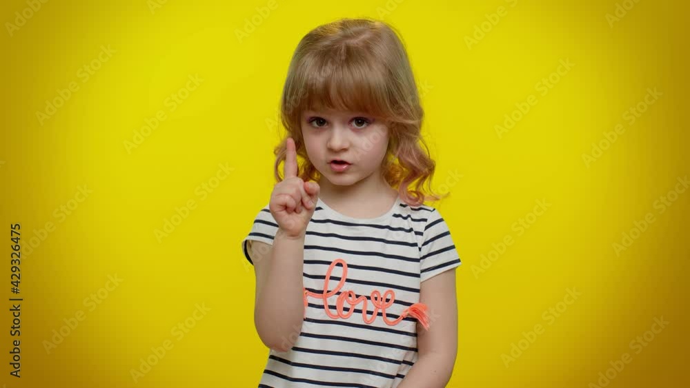 Hey you, be careful. Cute kid child girl 5-6 years old warning with admonishing finger gesture, saying no, scolding and giving advice to avoid danger, disapproval sign on yellow studio wall background Hey you, be careful. Cute kid child girl 5-6 years old warning with admonishing finger gesture, saying no, scolding and giving advice to avoid danger, disapproval sign on yellow studio wall background