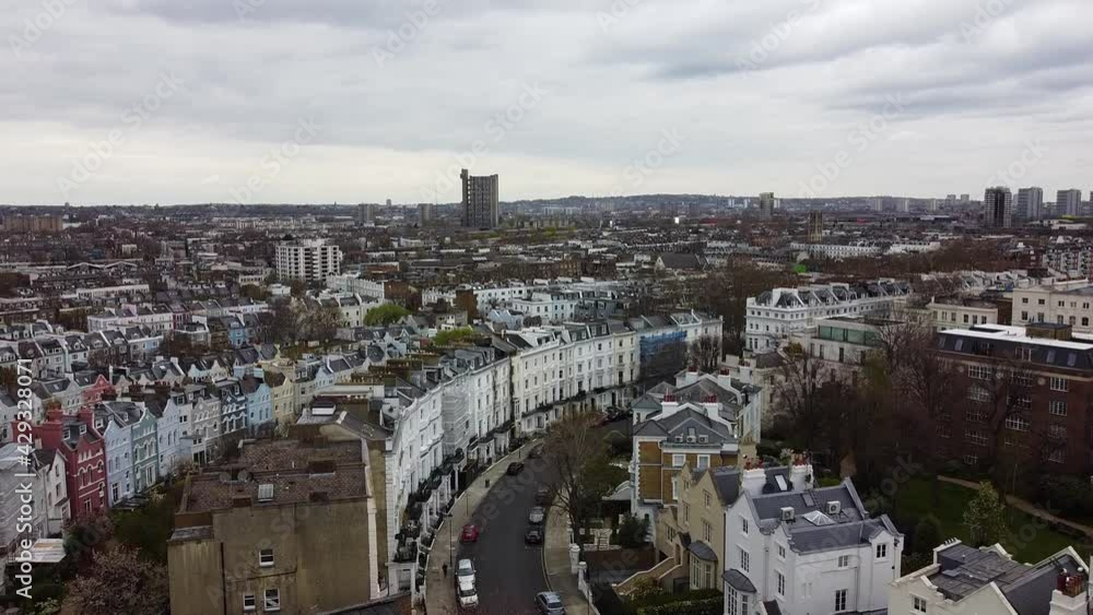 Ascending aerial wide shot over Notting Hill District with colorful buildings in housing area during cloudy day. London,Uk. Ascending aerial wide shot over Notting Hill District with colorful buildings in housing area during cloudy day. London,Uk.