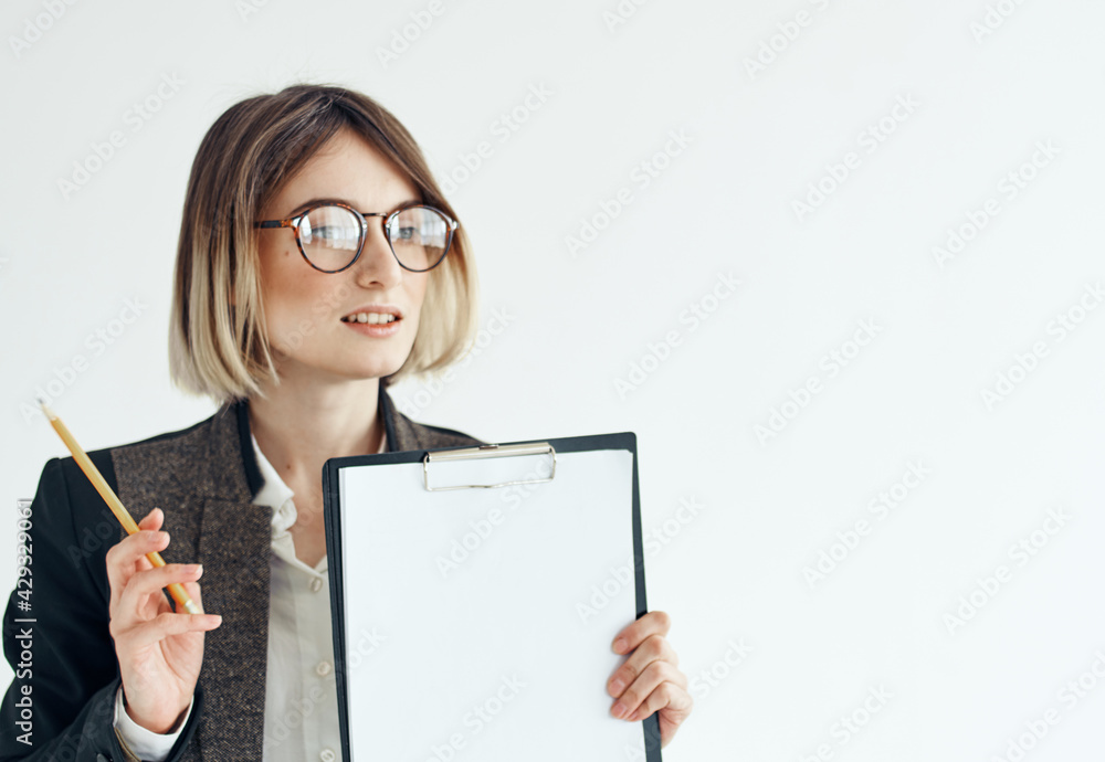 A woman in a jacket holds a folder with a white sheet of paper and glasses on her face A woman in a jacket holds a folder with a white sheet of paper and glasses on her face