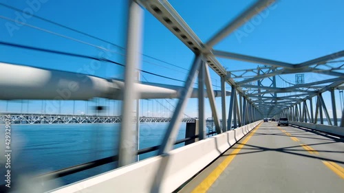 Real time footage showing the  crossing of famous Chesapeake  Bay Bridge (William Preston Lane Jr. Memorial Bridge) under metal latticework style pylon suspension beams. Towers on other side are seen.