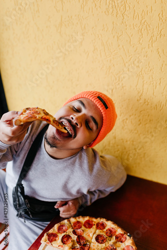 male model eating big pizza with his hand