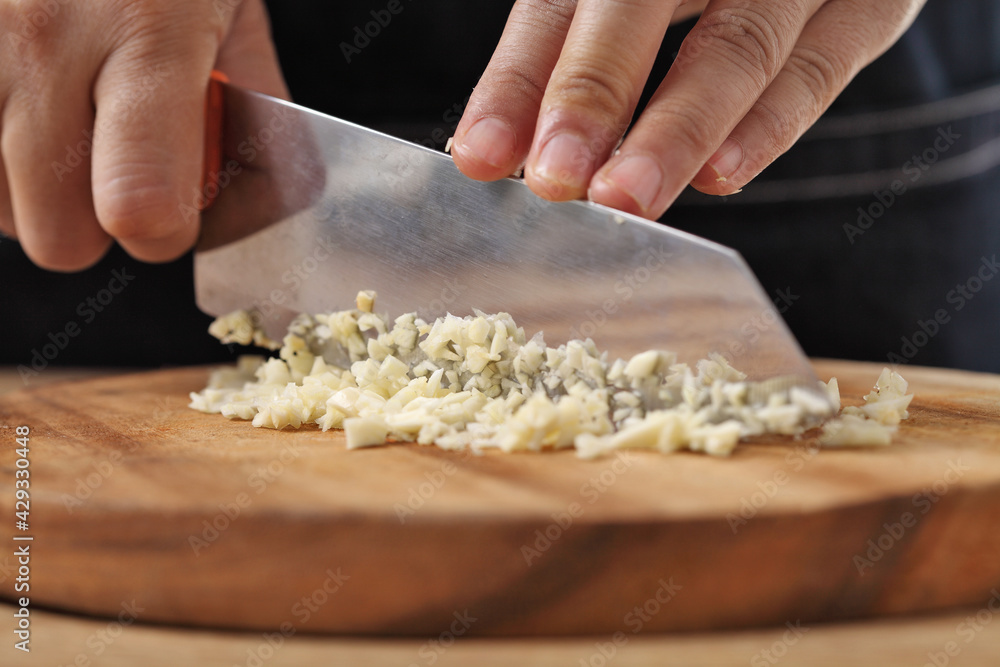 Chef chopped garlic on wooden cutting board