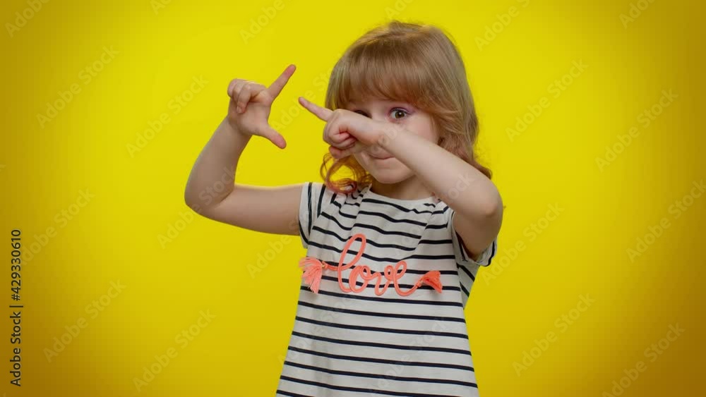 Funny blonde child girl showing loser gesture and pointing on you, blaming accusing for unsuccess, expressing disrespect, mocking your failure on yellow background. Teen kid children bullying abuse Funny blonde child girl showing loser gesture and pointing on you, blaming accusing for unsuccess, expressing disrespect, mocking your failure on yellow background. Teen kid children bullying abuse