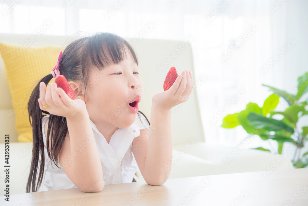 Pretty little asian girl eating strawberry at home. Healthy food and kid concept. Pretty little asian girl eating strawberry at home. Healthy food and kid concept.
