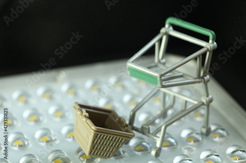 Miniature shopping trolley and basket represent retail and consumerism concept related idea. 