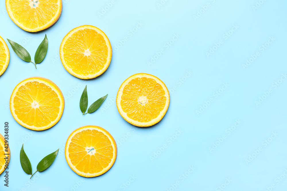 Slices of fresh oranges with green leaves on color background Slices of fresh oranges with green leaves on color background