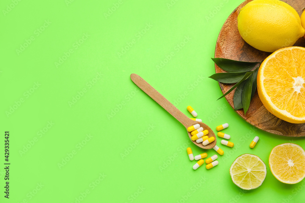 Spoon with vitamin C pills and citrus fruits on color background Stock