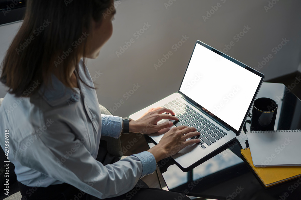 Side view of smiling young female office worker using computer laptop in office. Side view of smiling young female office worker using computer laptop in office.