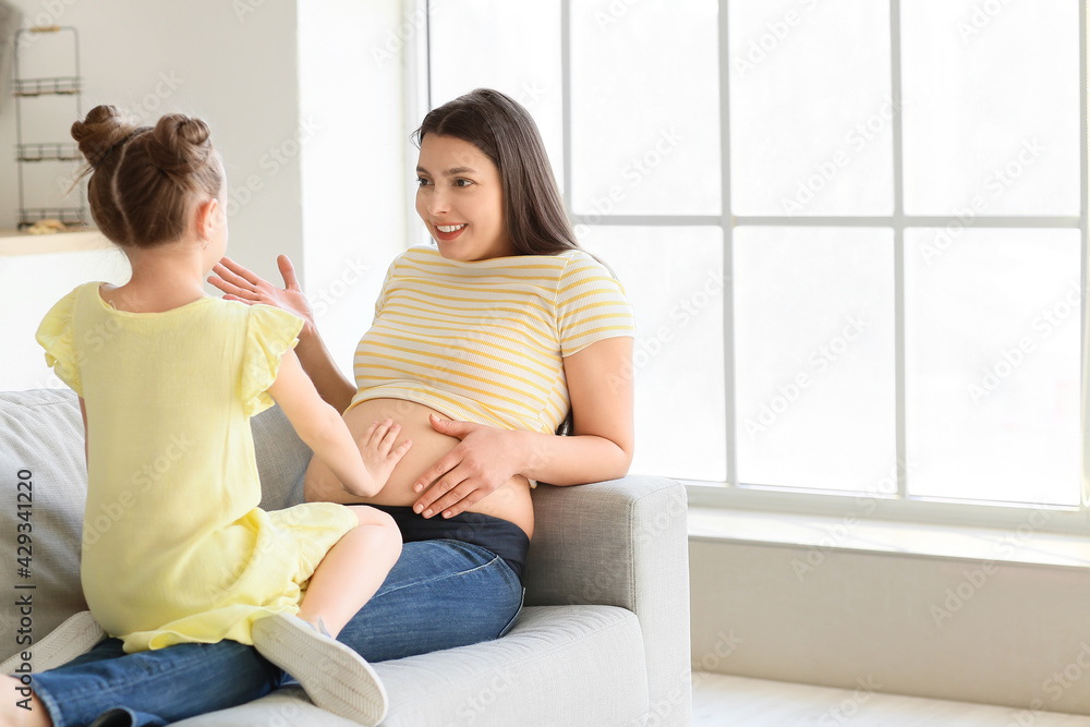 Young pregnant woman with her daughter at home Young pregnant woman with her daughter at home