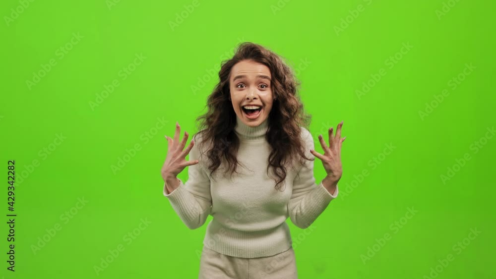 The woman is standing and looking at the camera. She is happy and waving her hands. She is clapping her hands and smiling. She is standing on a green background. Green screen. 4K The woman is standing and looking at the camera. She is happy and waving her hands. She is clapping her hands and smiling. She is standing on a green background. Green screen. 4K