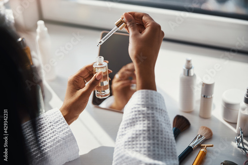 Canvastavla Young woman holding bottle of vitamin face serum