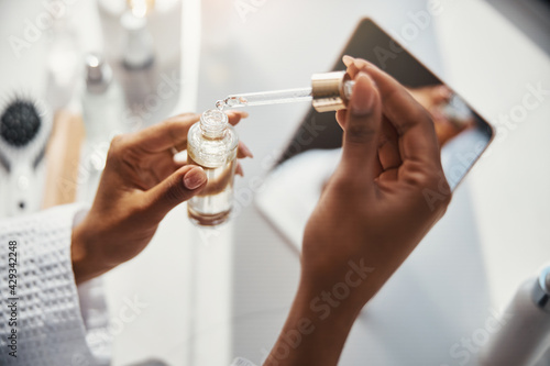 Female hands holding bottle of vitamin serum and pipette
