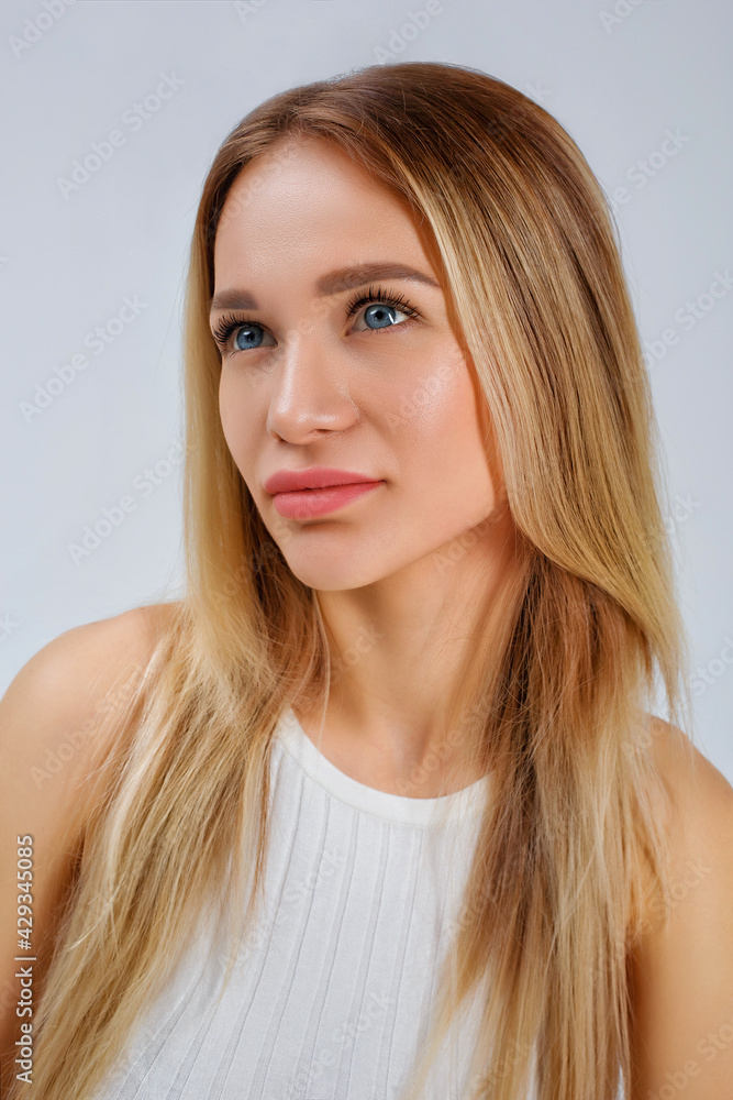 Large vertical portrait of a woman. Young beautiful blonde in a fashionable white T-shirt on a white background in the studio. Large vertical portrait of a woman. Young beautiful blonde in a fashionable white T-shirt on a white background in the studio.