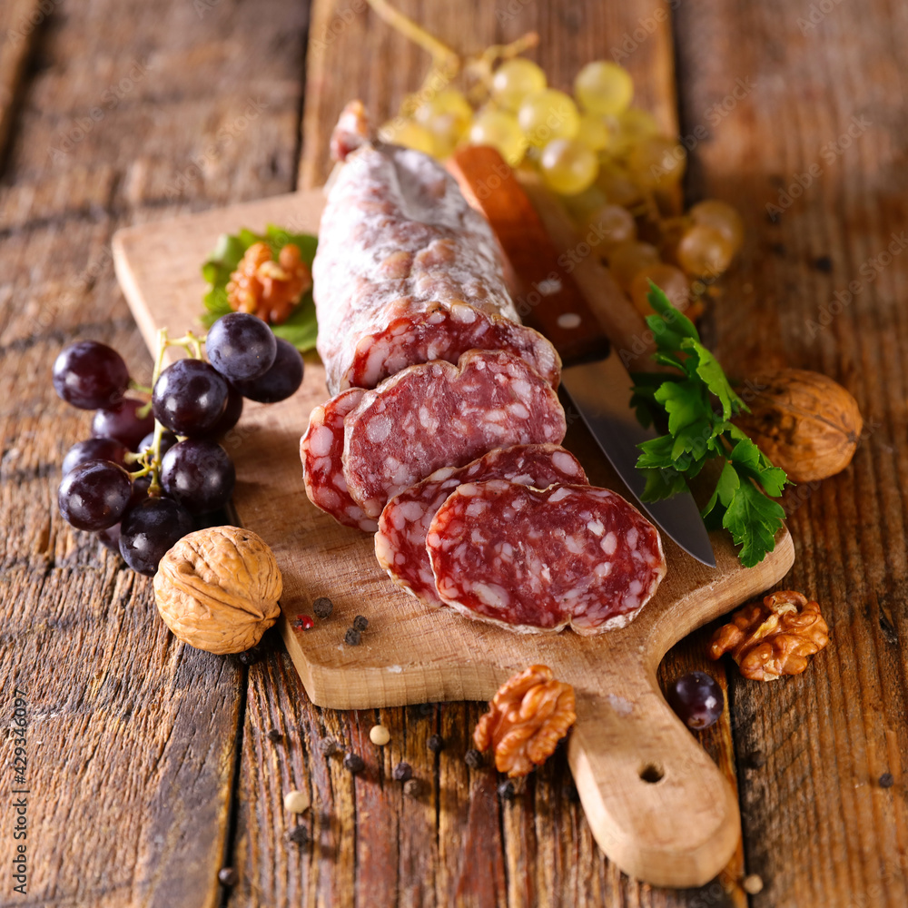 salami on wooden board with grapes and walnut salami on wooden board with grapes and walnut