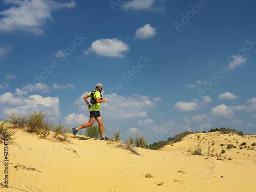 Athlete runs along the sandy desert. Desert trail running