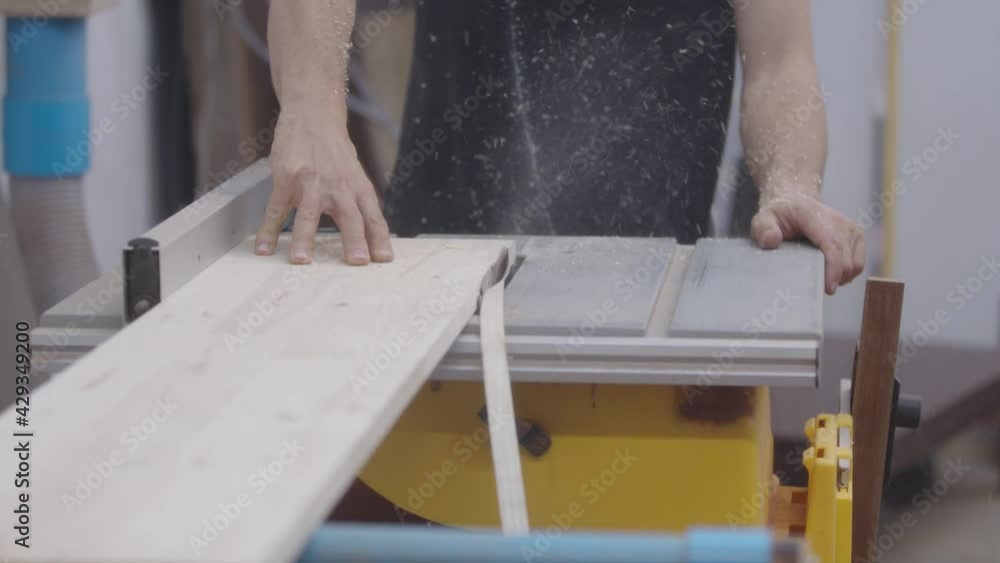 Carpentry or joinery workshop. Carpenter at work: sawing. Woodworking machinery: circular saw. Carpentry or joinery workshop. Carpenter at work: sawing. Woodworking machinery: circular saw.