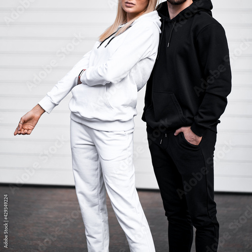 young bearded man and blonde girl is standing in plain hoodie for logo printing. Clothing mockup for hoodie. Autumn youngsters streetwear