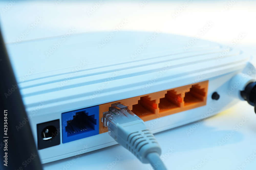 Connected cable to router on white table, closeup. Wireless internet communication Connected cable to router on white table, closeup. Wireless internet communication