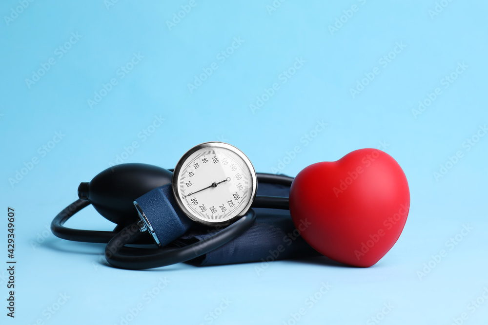 Blood pressure meter and toy heart on light blue background Blood pressure meter and toy heart on light blue background