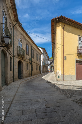 View at a old and narrow street with classic buildings on downtown Guimaraes city, couple walking on background