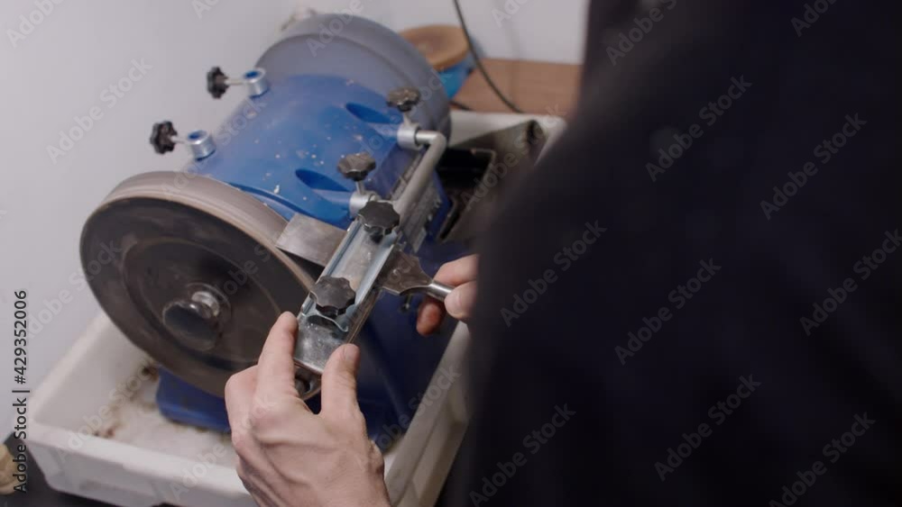 Carpenter at work. Sharpening chisel on the grinding stone. Carpenter at work. Sharpening chisel on the grinding stone.