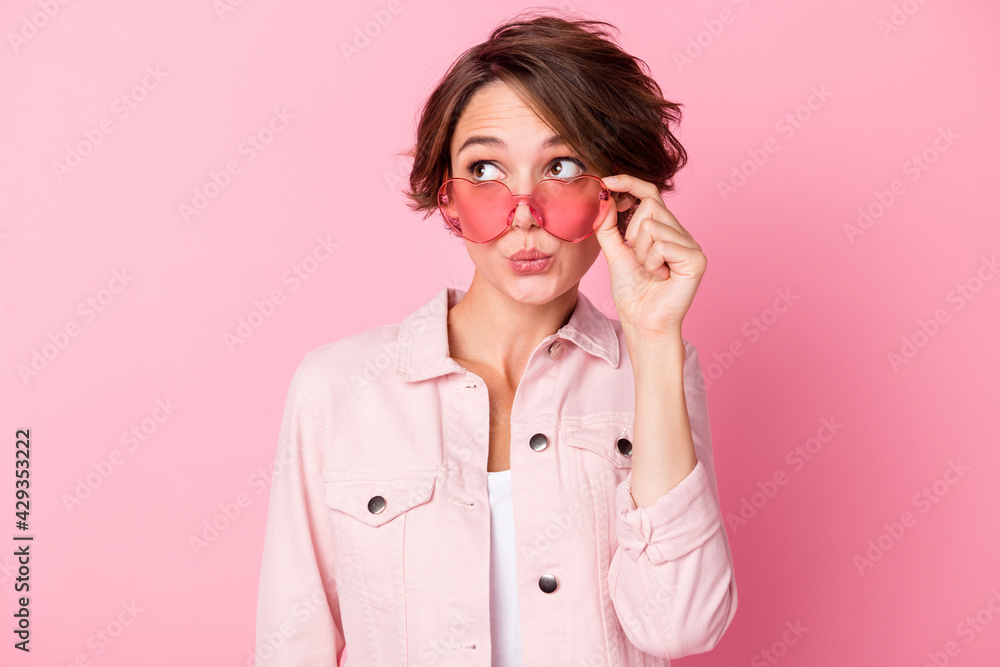 Photo portrait of kissing woman looking at blank space in rose-tinted heart-shaped glasses isolated on pastel pink colored background Photo portrait of kissing woman looking at blank space in rose-tinted heart-shaped glasses isolated on pastel pink colored background