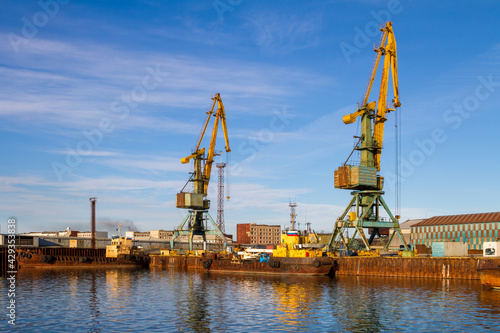Cargo seaport. View of old harbor cranes and rusty ships near the pier. Sea port in the Arctic. Industry and infrastructure in the Far North of Russia. Beringovsky, Chukotka, Siberia, Russia.