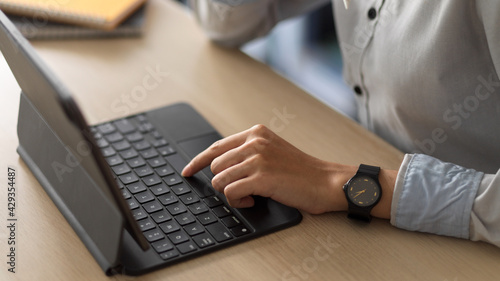 Side view of office worker hands using tablet with keyboard