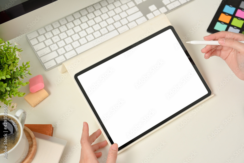 Top view of female designer hand working with digital tablet on workspace with designer supplies Top view of female designer hand working with digital tablet on workspace with designer supplies