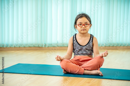 calmness and relax, female happiness.Horizontal, little asian girl meditates while practicing yoga class in school gym. freedom concept. calmness and relax, woman happiness. toned picture healthy life