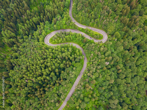 Aerial view of countryside road passing through the forest and mountain