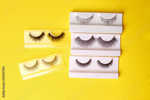 Flat lay composition of professional makeup tools and false eyelashes on bright yellow background  space for text. Concept of make-up artist  beauticisan industry  salon flyer